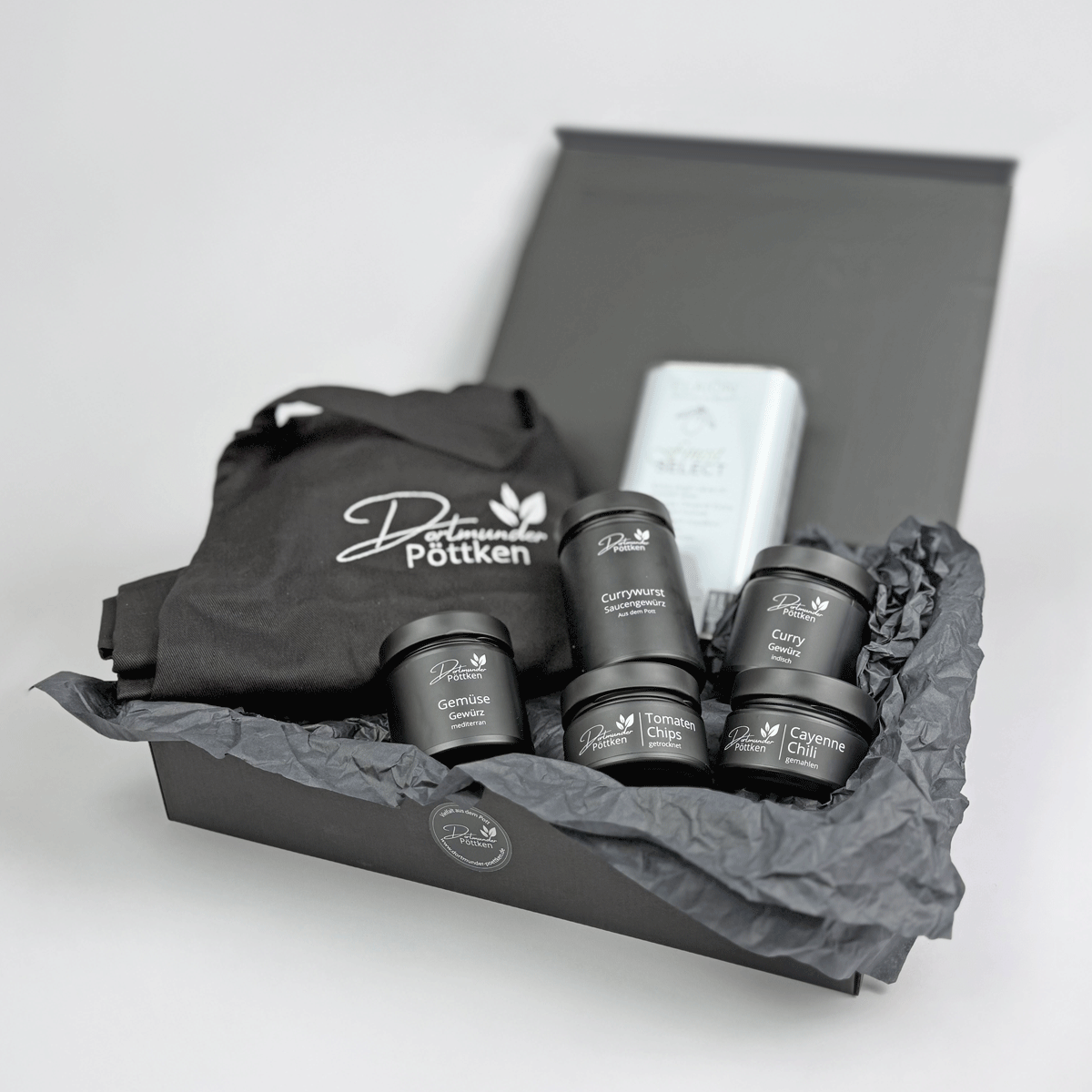 Geschenkset mit schwarzer Schuerze_ Olivenoel und fuenf Dortmunder Poettken Gewuerzen in offener Box