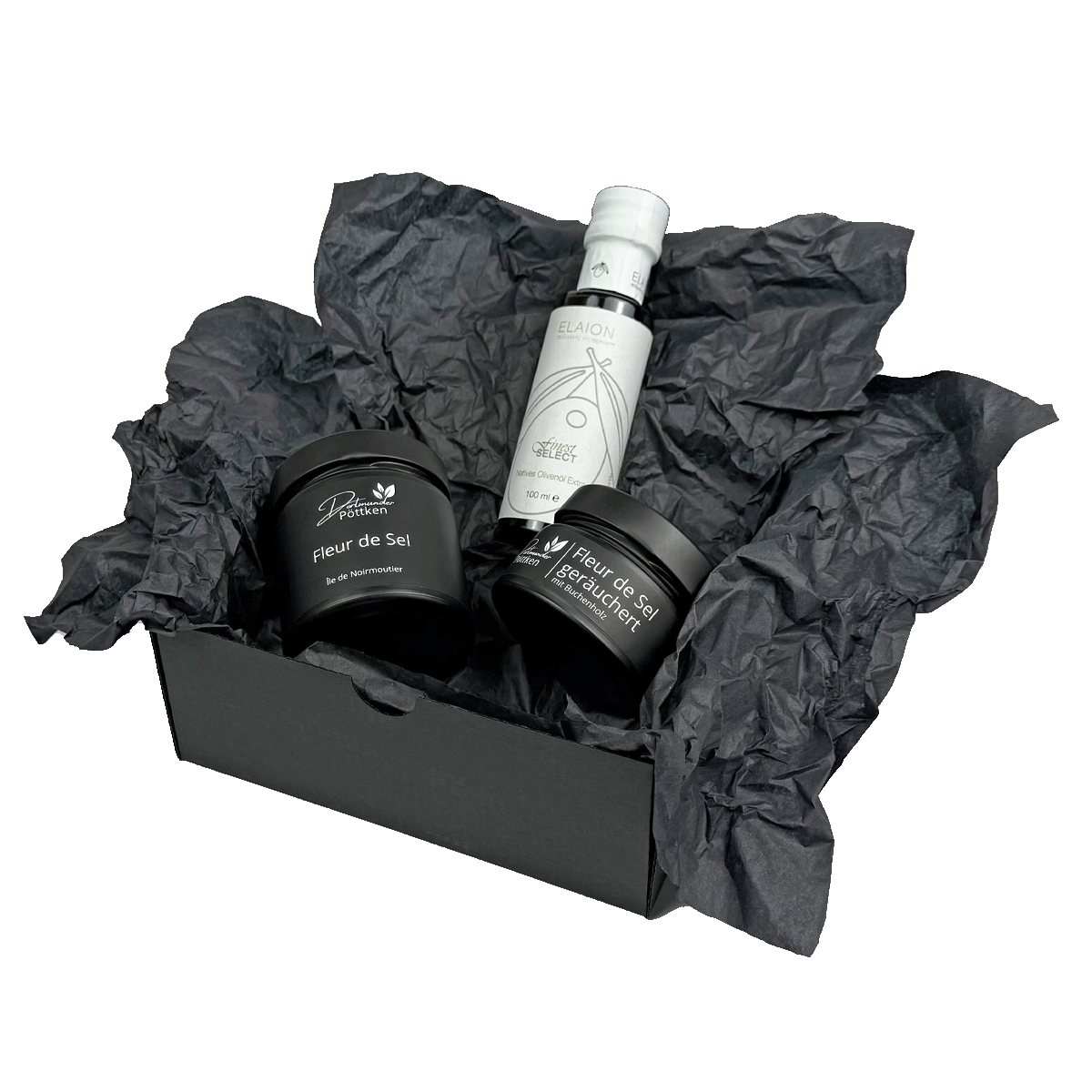 Offene Geschenkbox mit Fleur de Sel geraeuchert_ Fleur de Sel und Olivenoel in schwarzem Papier dekoriert